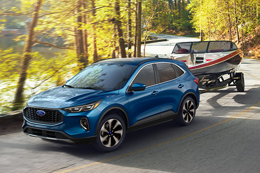 Ford Escape towing a boat driving in woods from used car dealer near Tampa FL